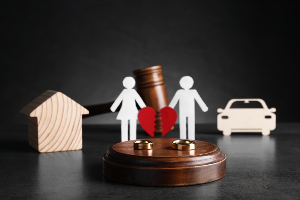 Gavel with house, car, rings, and family figures representing asset division in divorce